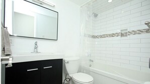 Une salle de bain moderne avec un lavabo blanc, des meubles noirs, des toilettes et un espace douche.