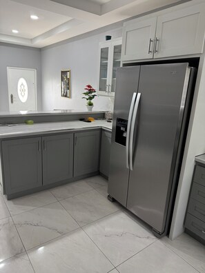 A modern kitchen with grey cabinets, a stainless steel refrigerator, and a white countertop. - Charming 2-bedroom apartment with WiFi, AC in fabulous Tacarigua (Tacarigua)