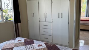 Een slaapkamer met een grote kledingkast, een bed en een raam met gordijnen.
