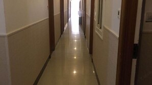 A long, narrow hallway with a tiled floor and wooden doors on both sides. - Yongshun Hotel (Shanghai)