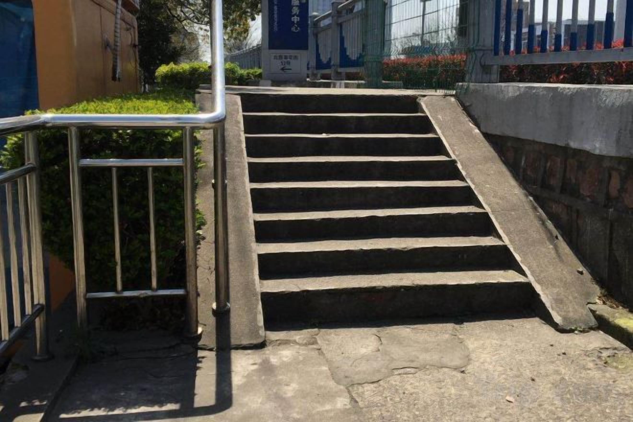 Un conjunto de escalones de hormigón con barandillas metálicas a ambos lados, que conducen a una entrada.
