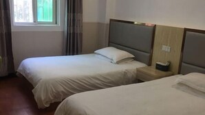 A hotel room with two single beds, a window with curtains, a bedside table with a lamp, and a wooden headboard. - Yongshun Hotel (Shanghai)