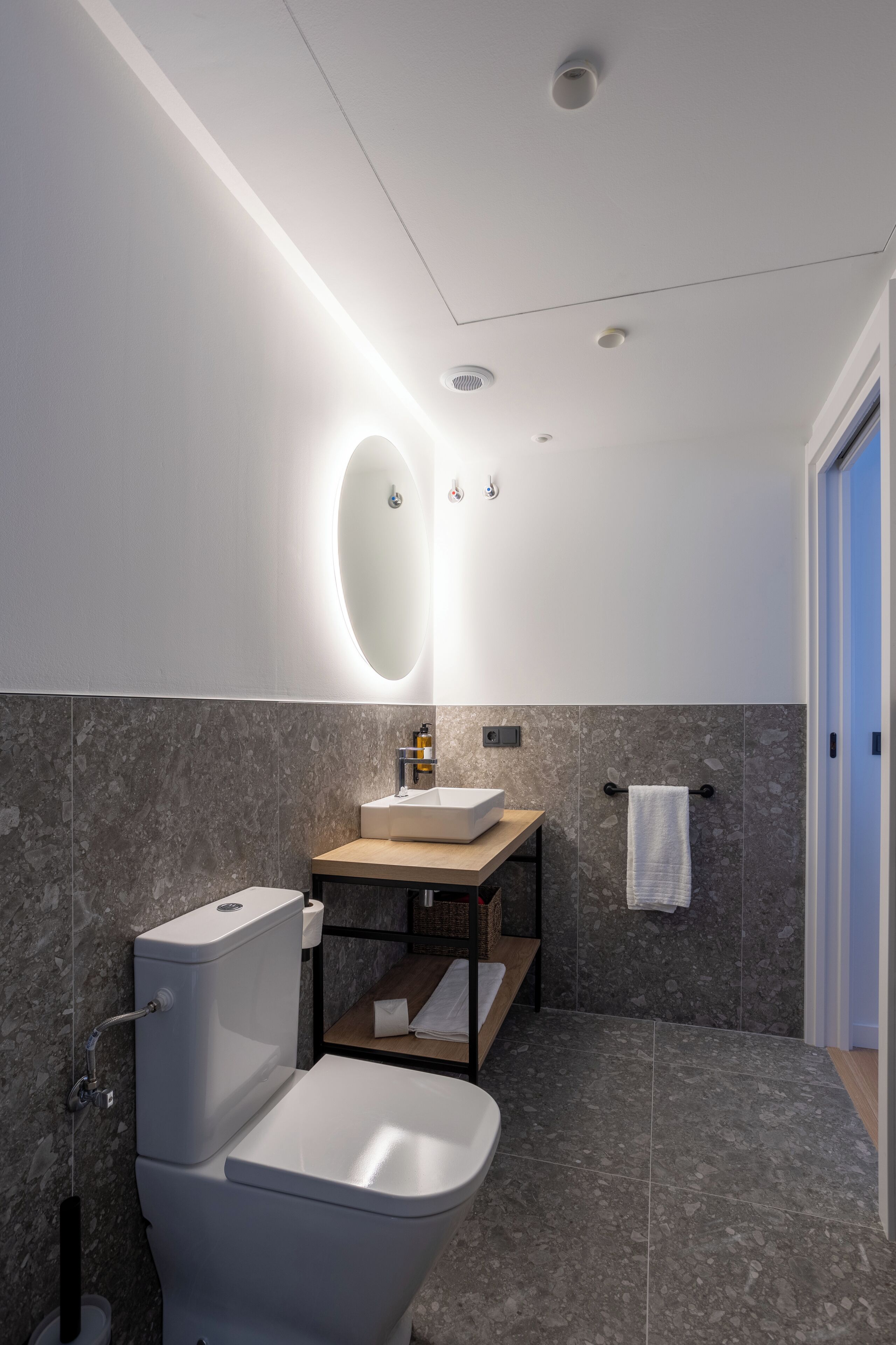 Une salle de bain moderne avec des toilettes, un lavabo et un miroir.