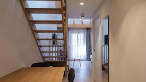 A modern interior with a wooden staircase, a dining area with a table and chairs, and a large mirror on the wall. - Be10 Suites (Bermeo)