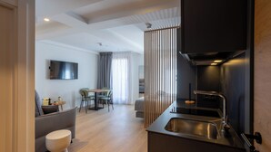A modern kitchen with a built-in stove, a sink, and a dining area with a table and chairs. - Be10 Suites (Bermeo)