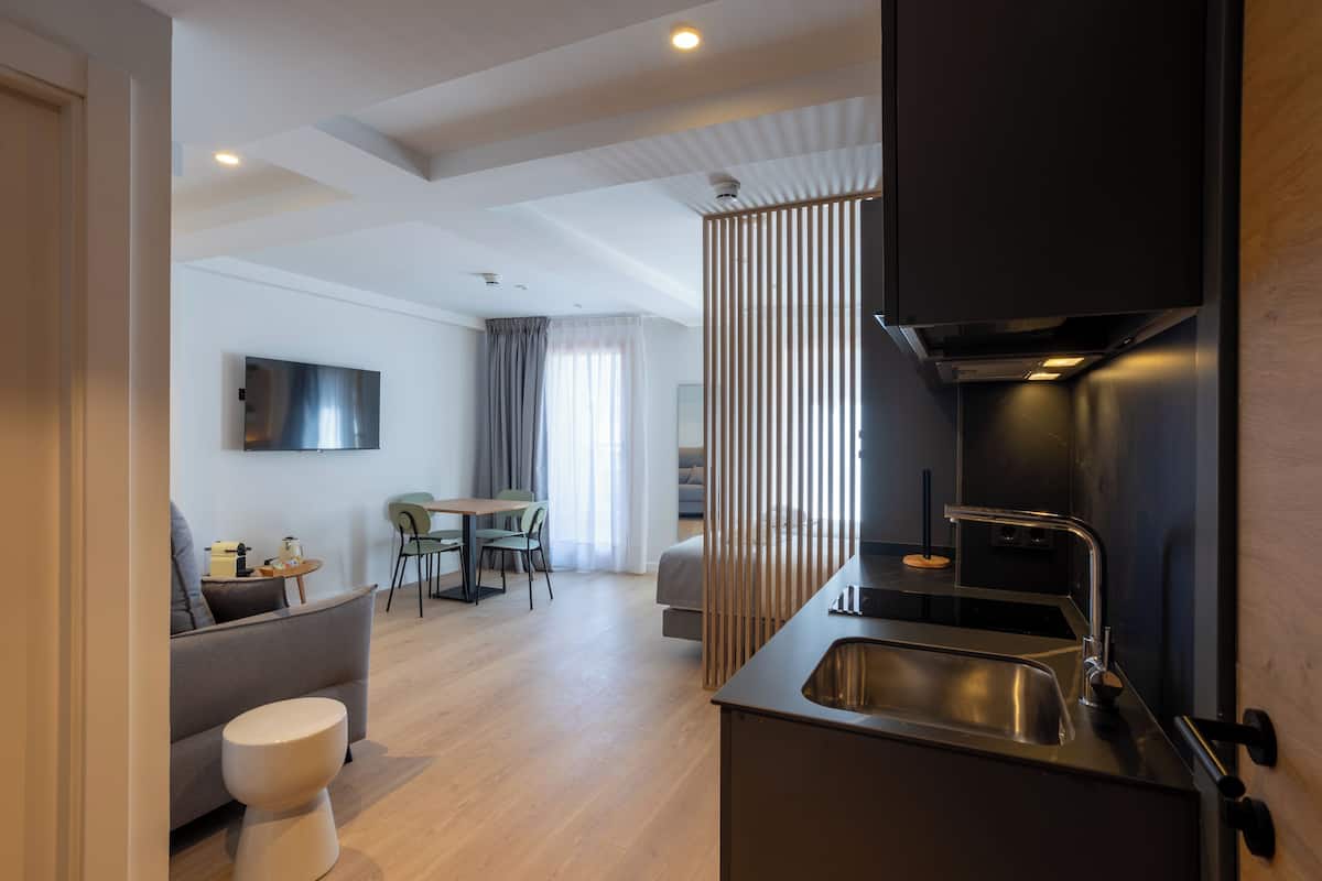 A modern kitchen with a built-in stove, a sink, and a dining area with a table and chairs.