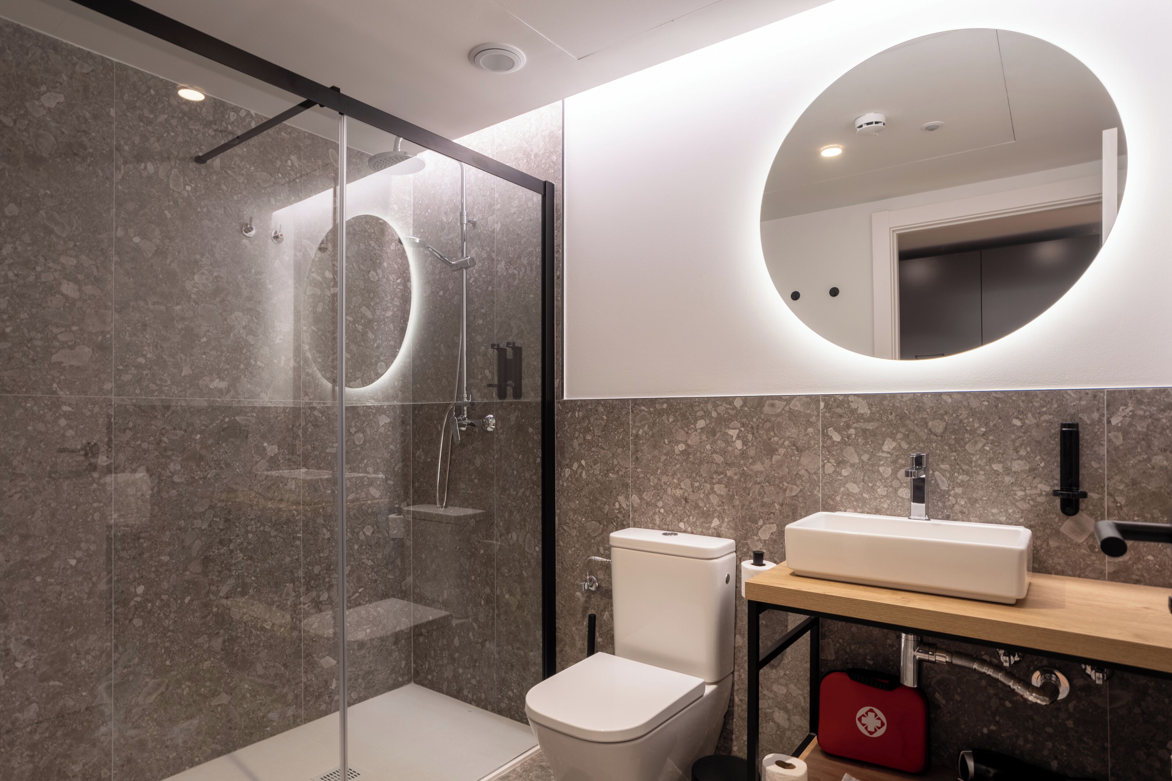 Une salle de bain moderne avec une douche à parois de verre, des toilettes et un lavabo avec un miroir au-dessus.