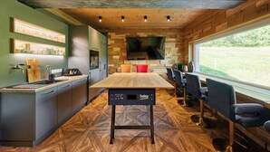 A modern kitchen with a wooden table, bar stools, and a large window. - Sunny, stylish studio in the mountains (Královéhradecký kraj)