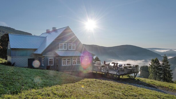 A house with a sloped roof, a fenced yard, and a deck with outdoor seating. - Sunny, stylish studio in the mountains (Královéhradecký kraj)