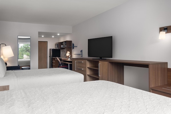 Quarto de hotel moderno com duas camas, uma escrivaninha, uma TV e um guarda-roupa.