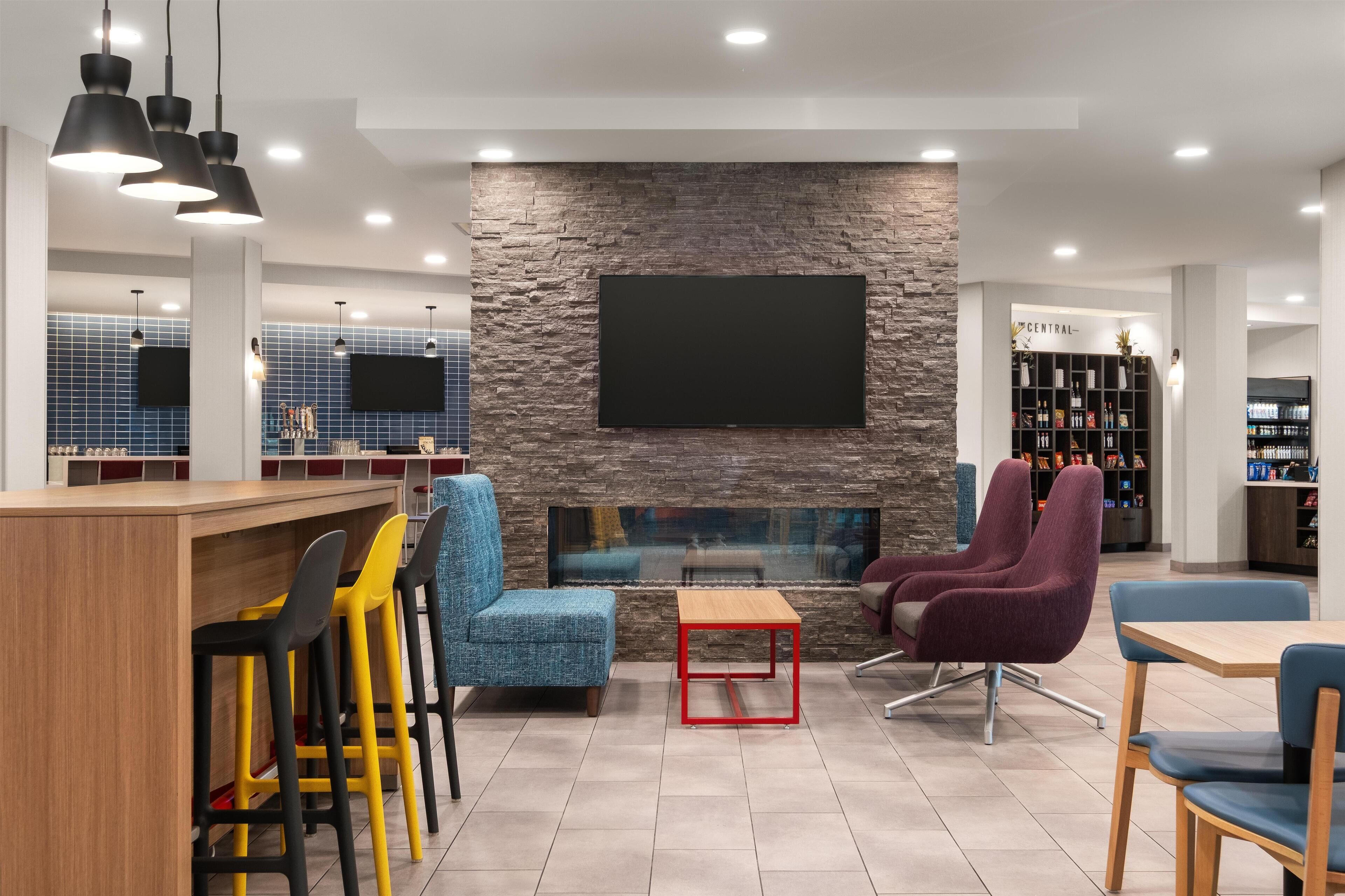 A modern lounge area with a stone wall, a flat-screen TV, and a bar with stools.