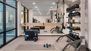 Uma academia com equipamentos de exercício, um espelho e grandes janelas.