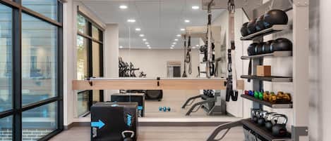 A gym with exercise equipment, a mirror, and large windows.