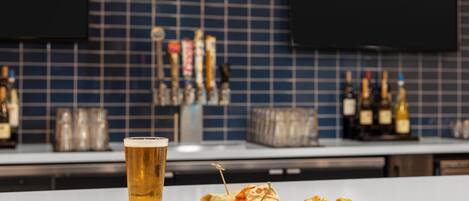 Un bar con una jarra de cerveza, una bandeja de comida y una pared de azulejos con utensilios de bar.