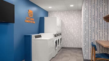 A laundry room with a blue wall, a sign that says "Let's have loads of fun," and a washing machine.