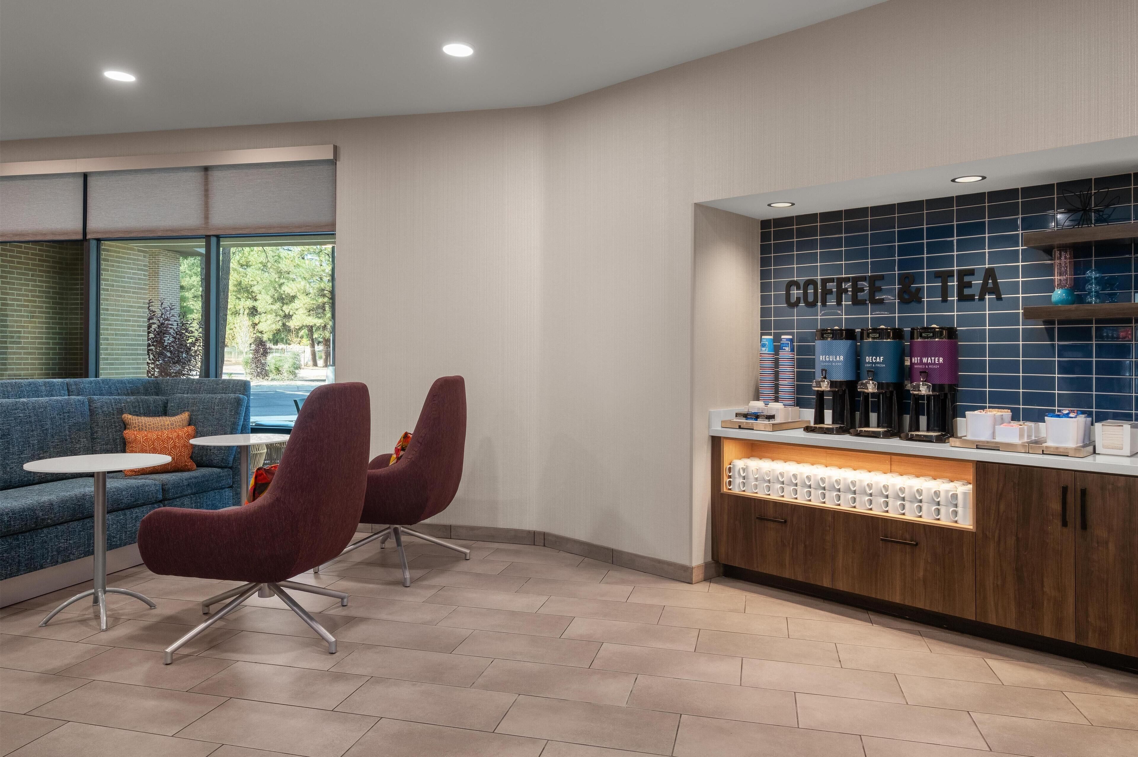 A modern coffee and tea station with seating and a view of the outdoors.
