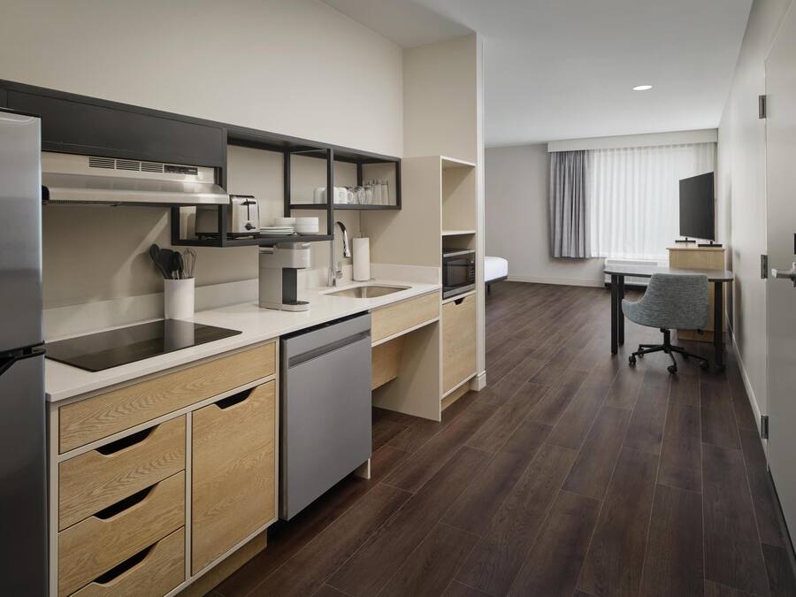 A modern kitchen with built-in appliances, a dining area with a table and chairs, and a view of the city.