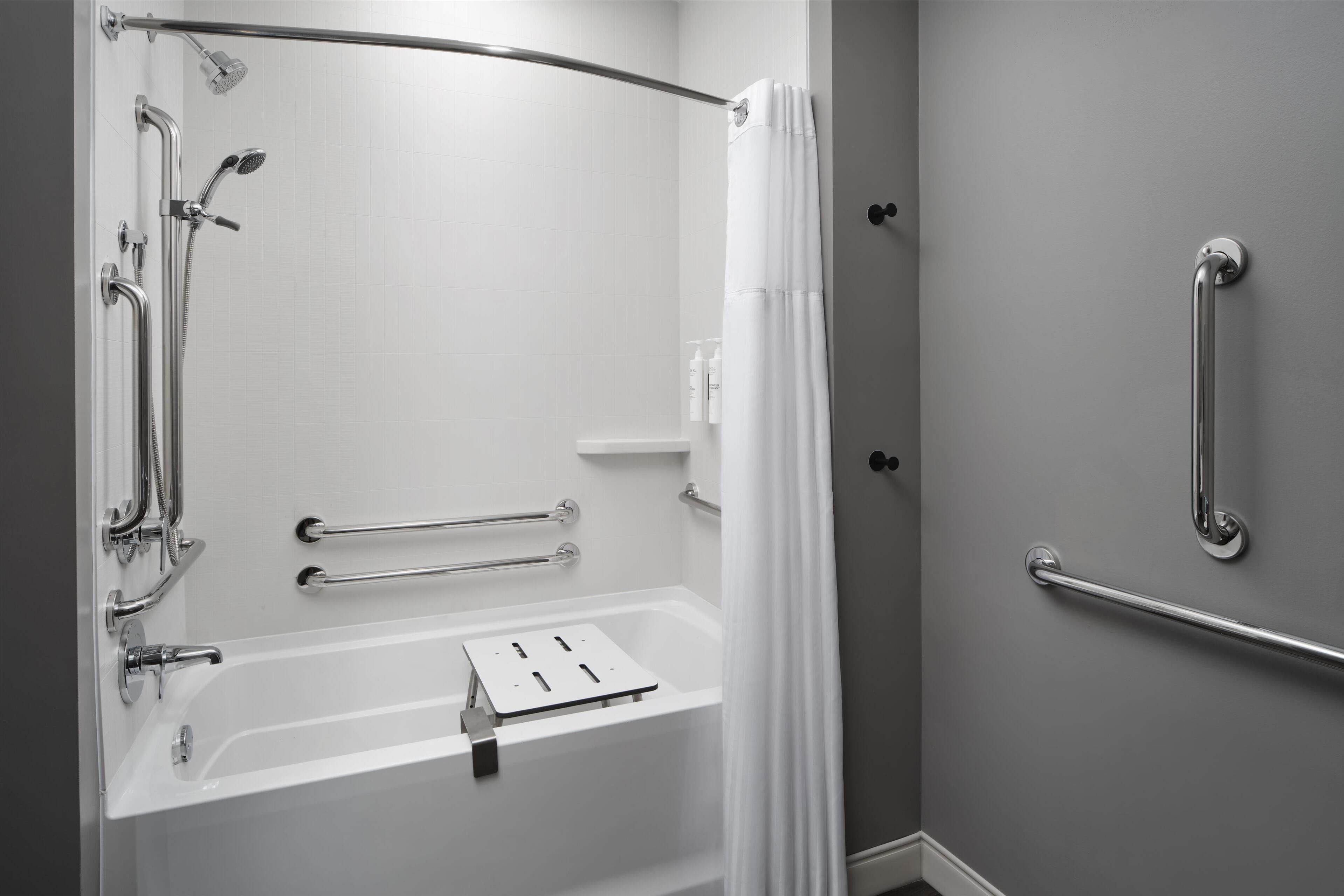 A modern bathroom with a walk-in shower, grab bars, and a white bathtub.