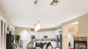 A spacious dining area with a long table, chairs, and a modern kitchen in the background. - Luxe Retreat- Private Pool -BBQ- Peaceful Retreat- Comfort-Relax-Prime Location (Mesa)