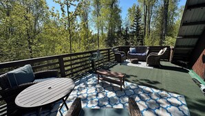 A covered outdoor patio with a round table, two chairs, a sofa, and a bench. - Charming loft cabin just 7 minutes from downtown (Talkeetna)