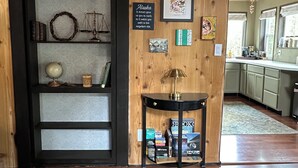 A wooden interior with a bookshelf, a framed quote, a globe, and a small table. - Charming loft cabin just 7 minutes from downtown (Talkeetna)