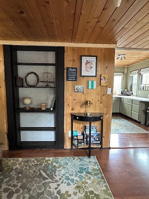 A wooden interior with a bookshelf, a framed quote, a globe, and a small table. - Charming loft cabin just 7 minutes from downtown (Talkeetna)