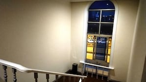 A staircase with a handrail leading to a landing. A large window with a view of a parking lot and a building is visible. - Xinsihai Hotel (Ningbo)