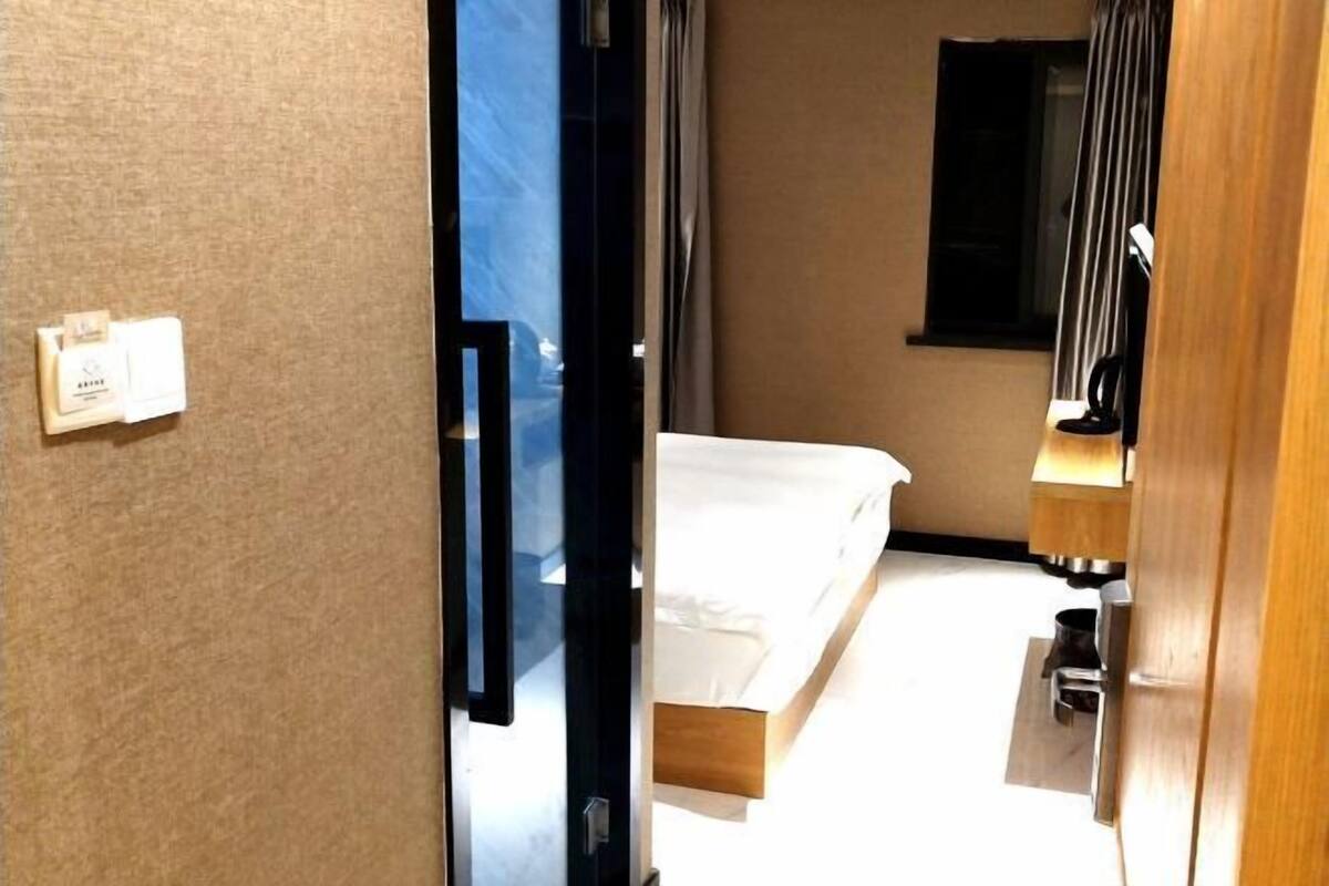 A hotel room with a bed, a mirror, a wooden nightstand, and a window with curtains.