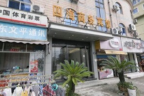 A building with multiple storefronts, including a clothing store and a restaurant. - Xinsihai Hotel (Ningbo)