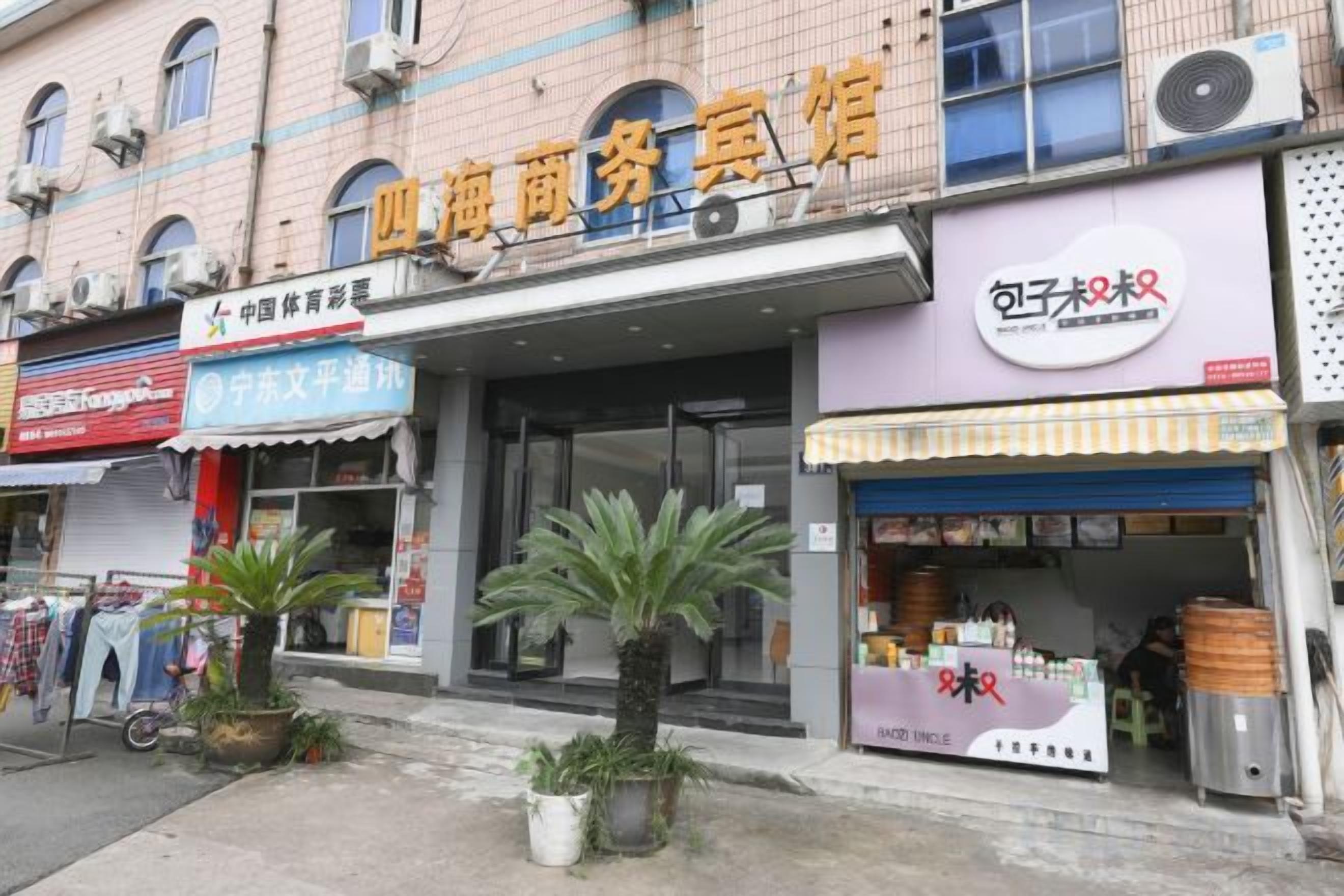 A commercial building with multiple storefronts, including a visible sign for a business named '四海商务宾馆'.