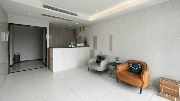 A modern hotel lobby with a reception desk, seating area, and a visible trash bin. - Xinsihai Hotel (Ningbo)