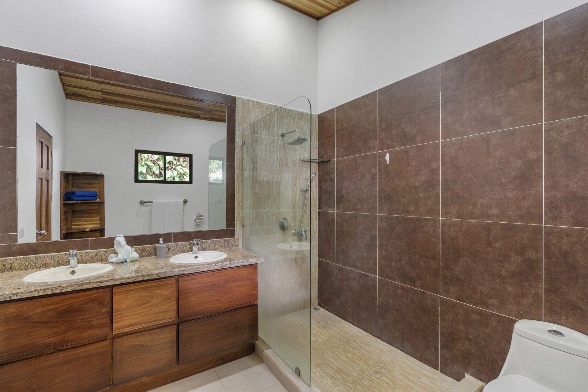 A bathroom with two sinks, a glass shower enclosure, and a large mirror.