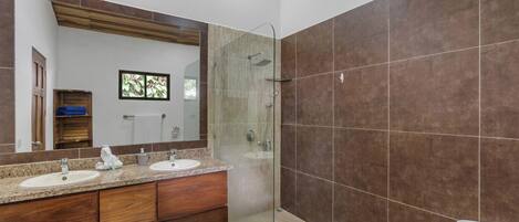 A bathroom with two sinks, a glass shower enclosure, and a large mirror.
