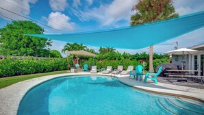 A swimming pool with lounge chairs and a shaded area. - Relax & Recharge: Saltwater Pool + Lush Backyard Oasis in Palm Beach Gardens (Palm Beach Gardens)