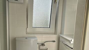 Ein kleines, kompaktes Badezimmer mit Toilette, Fenster und Waschbecken.