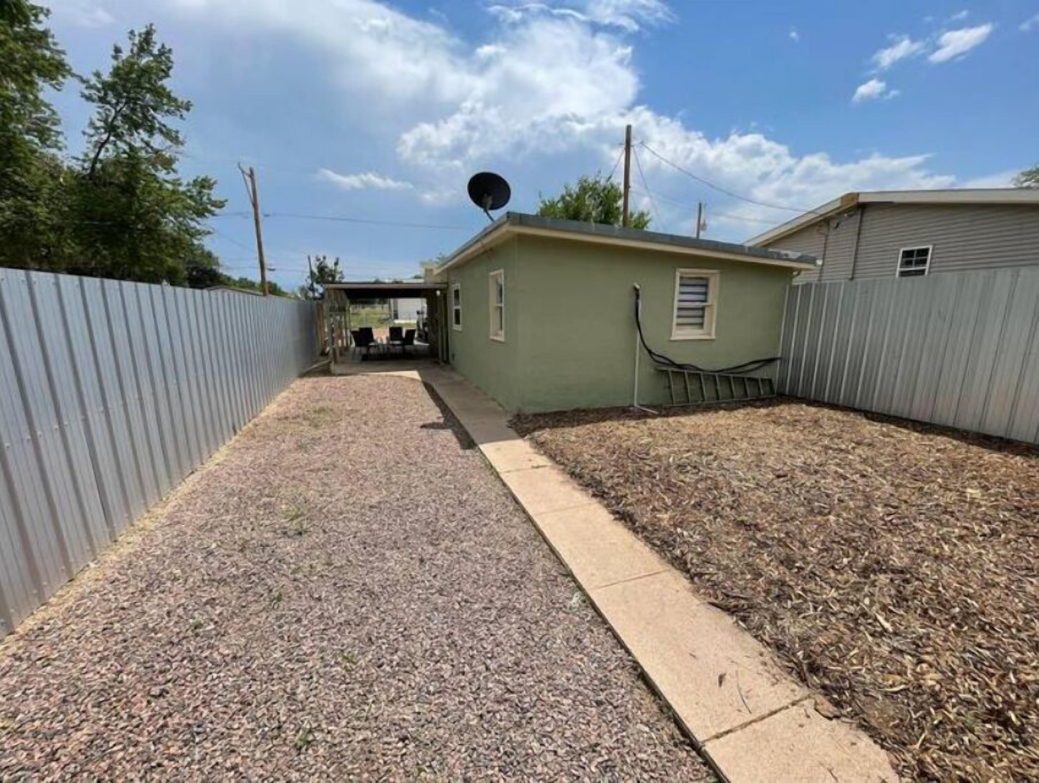 A covered patio area with a gravel path leading to a small building.
