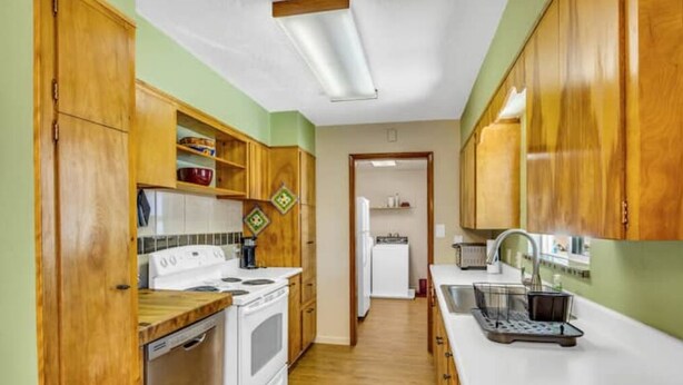 A kitchen with wooden cabinets, a white stove, and a dishwasher.