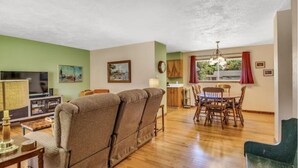 A living room with a sofa, television, and dining area with chairs and a table.