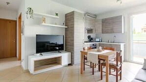 A modern living room with a flat-screen TV, a dining area with a table and chairs, and a kitchen with cabinets and appliances. - Fox's House - Apartment with private parking near Florence (Campi Bisenzio)