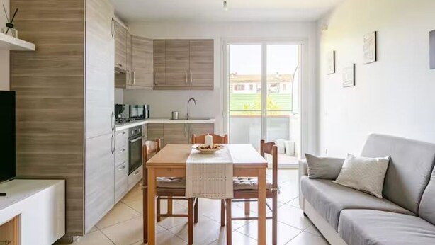 A modern kitchen with wooden cabinets, a dining table with chairs, a sofa, and a TV. - Fox's House - Apartment with private parking near Florence (Campi Bisenzio)