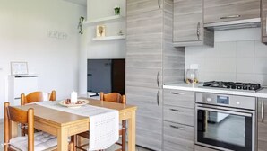 A modern kitchen with a wooden dining table, built-in cabinets, and a stainless steel oven. - Fox's House - Apartment with private parking near Florence (Campi Bisenzio)