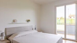 A bedroom with a bed, bedside tables, and a window with a view of the outside. - Fox's House - Apartment with private parking near Florence (Campi Bisenzio)