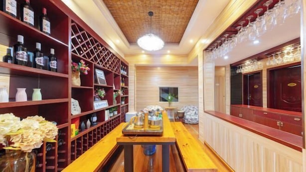 Un rincón de bar acogedor con estanterías de madera, una mesa central y una lámpara colgante.