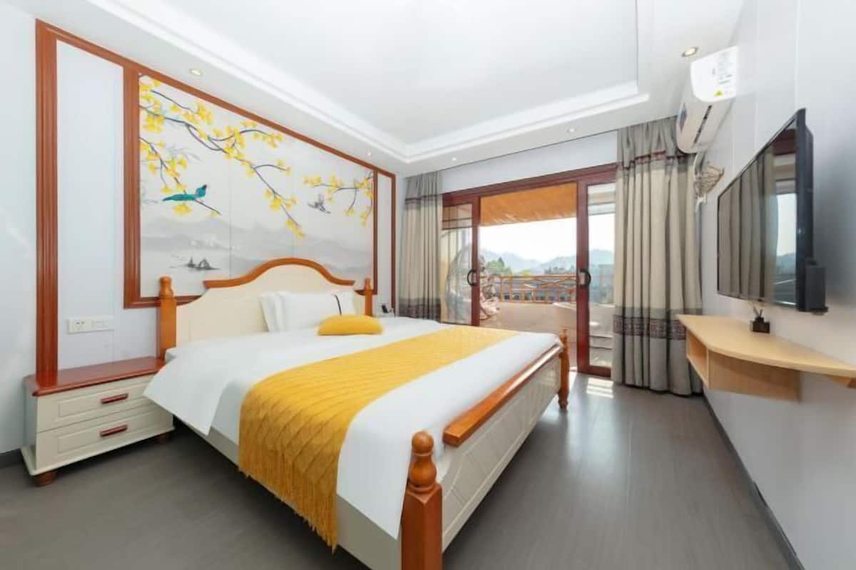 Une chambre d’hôtel avec un lit, un tableau, une télévision et un balcon avec des rideaux.
