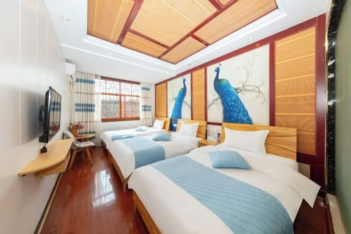 Une chambre d’hôtel avec deux lits, une télévision, un bureau et une fenêtre avec des rideaux.