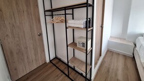 Ein begehbarer Kleiderschrank mit Holzböden, einer weißen Tür und einem Bett mit weißer Bettdecke.