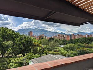 A view from a balcony with a cityscape, including buildings and mountains in the background. - CAVE (Medellín)