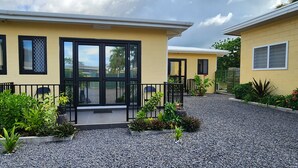 A yellow building with a black-framed entrance and a gravel driveway. - Fugalei Motel (Apia)