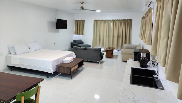 A modern hotel room with a bed, sofa, armchair, dining table, and kitchenette. - Fugalei Motel (Apia)