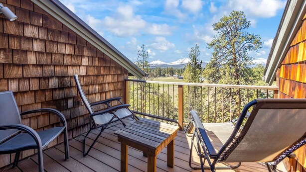 A wooden deck with outdoor furniture, a view of snow-capped mountains, and a clear sky. - Sisters Chalet 1-bed retreat with WiFi, AC, and views near downtown Sisters. (Sisters)